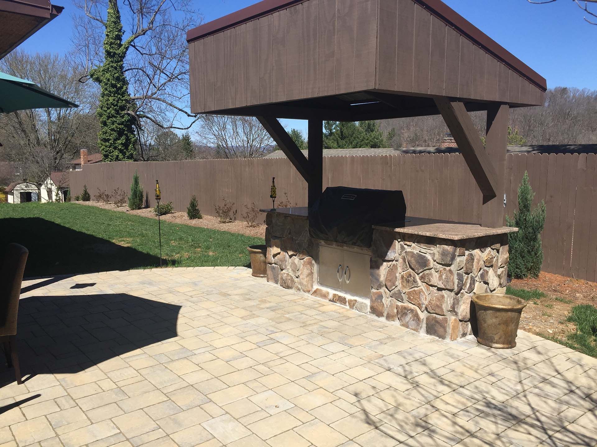 A patio with a wooden gazebo and a kitchen outdoor