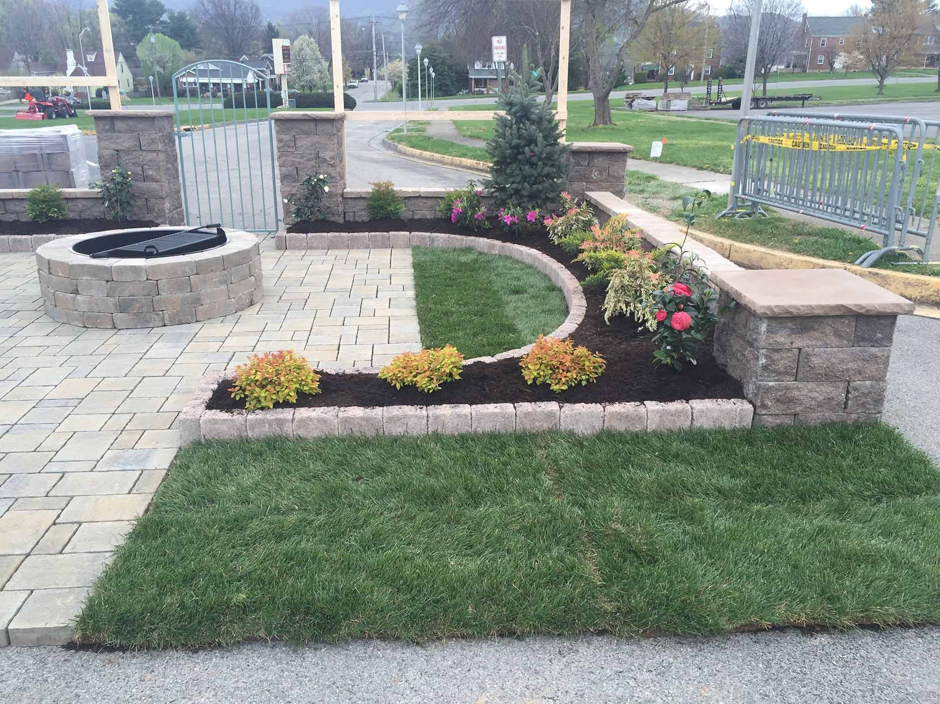 A brick patio with a fire pit and flowers