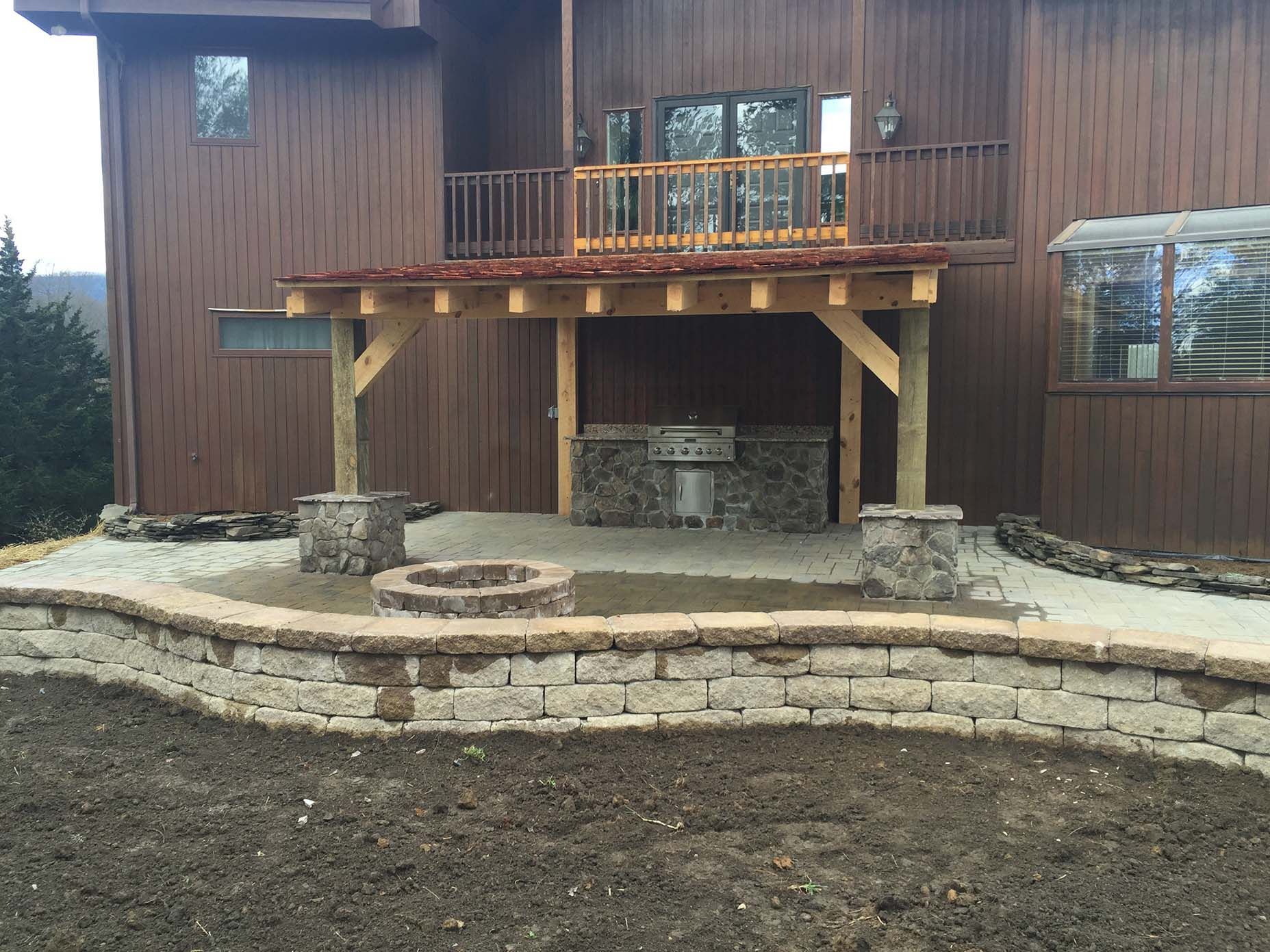 A large wooden house with a fire pit and kitchen in front of it