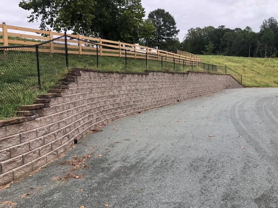 A retaining wall along the side of a road next to a fence