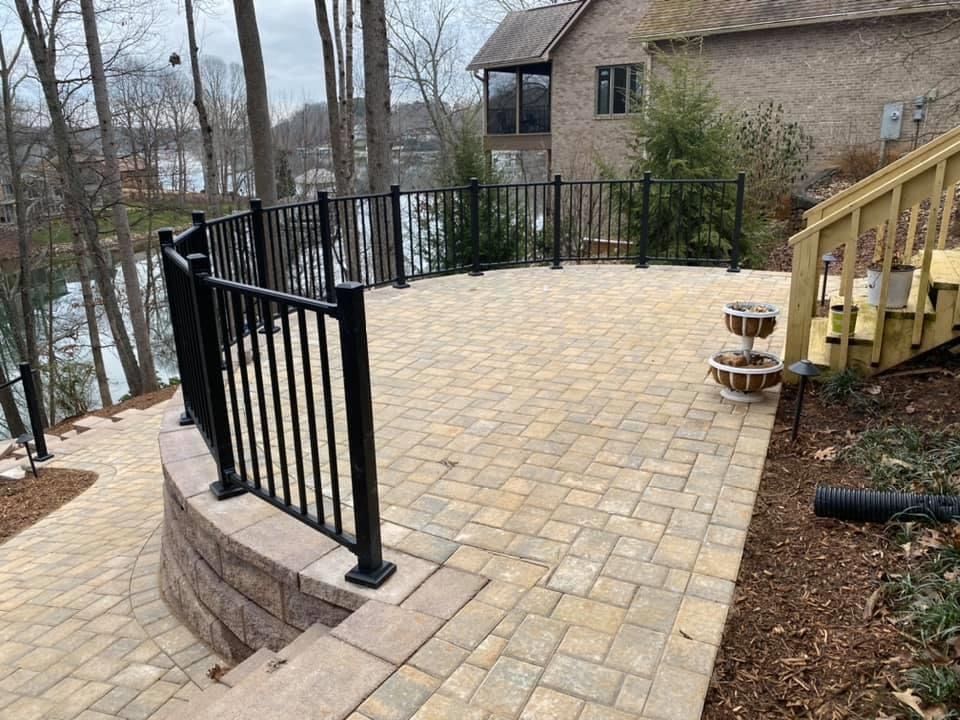 A patio with a black railing and stairs next to a house