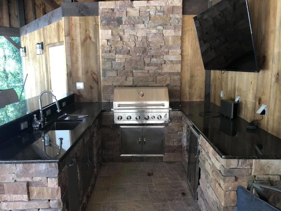 A kitchen with a grill, sink, and television