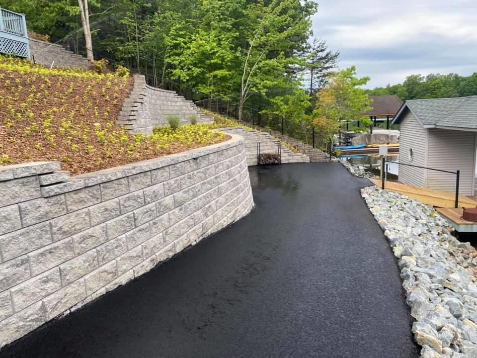 A brick wall along the side of a driveway next to a house