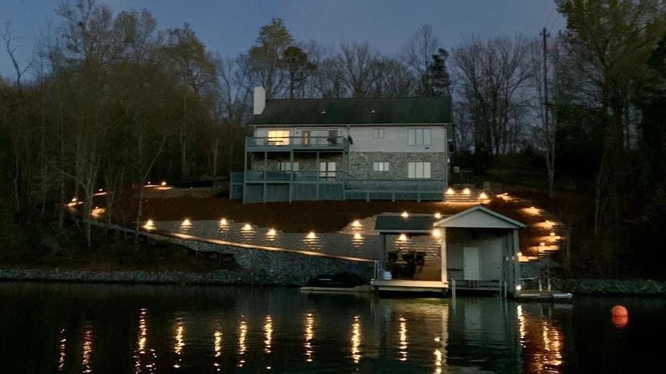 A large house is sitting on top of a hill next to a body of water