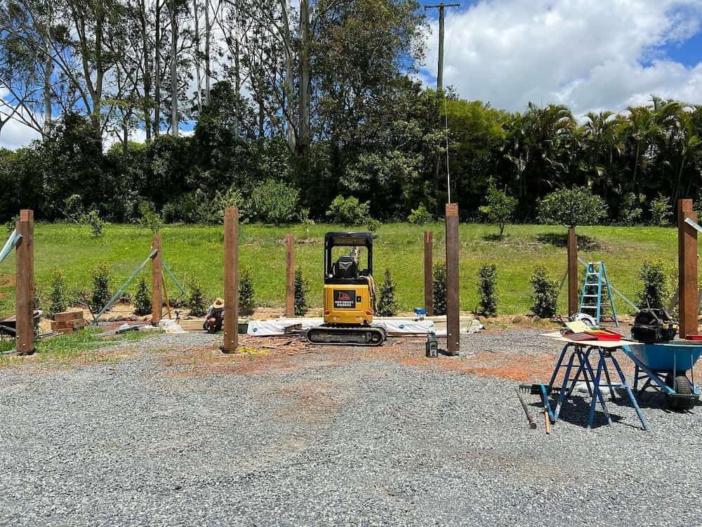 A Small Yellow Excavator is Parked in a Gravel Lot Next to a Wheelbarrow — Norcoast Diggers in Ballina, NSW