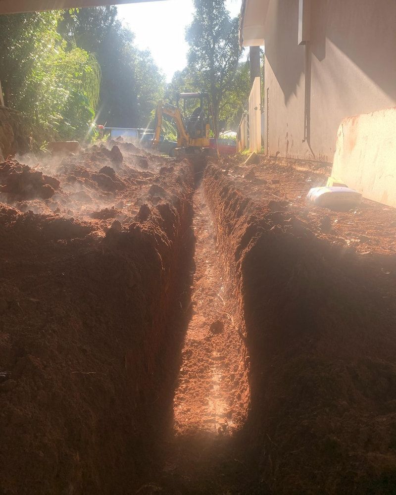 A Man is Digging a Trench in the Dirt in Front of a House — Norcoast Diggers in Ballina, NSW