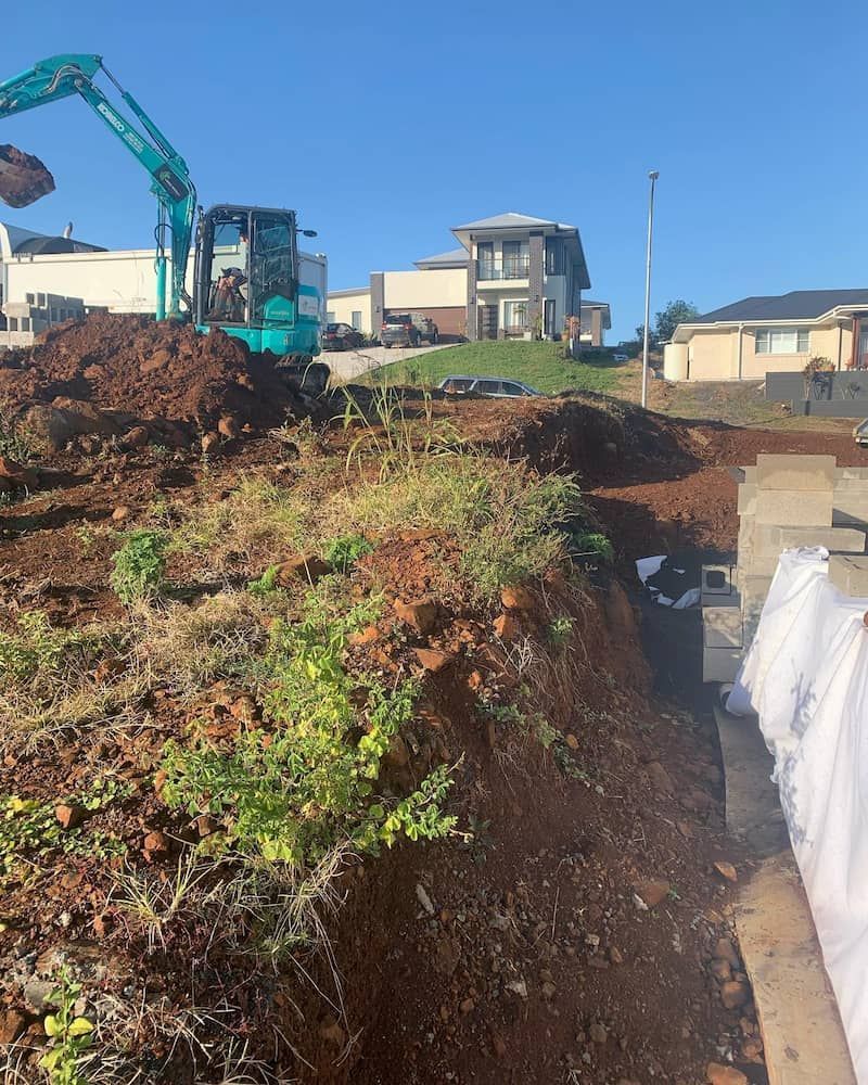 A Construction Site With a Large Pile of Dirt and a House in the Background — Norcoast Diggers in Ballina, NSW