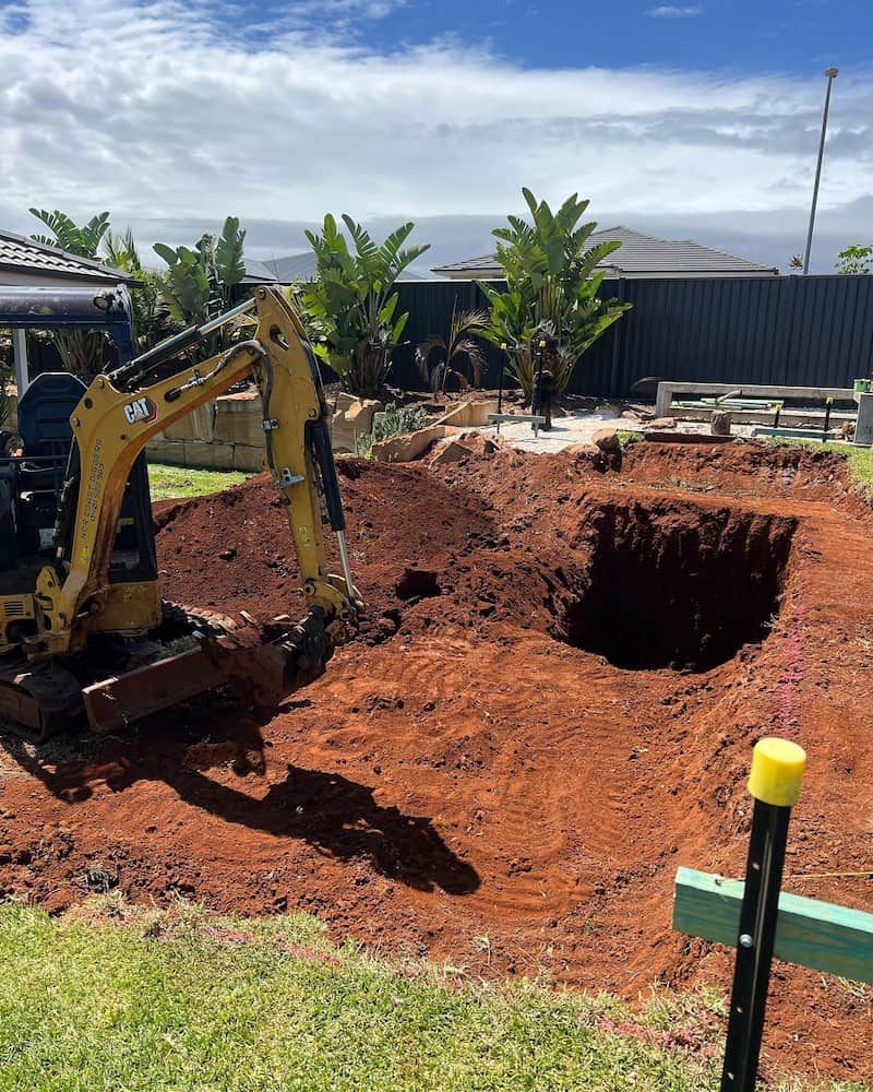 A Yellow Excavator is Digging a Hole in the Ground — Norcoast Diggers in Byron Bay, NSW