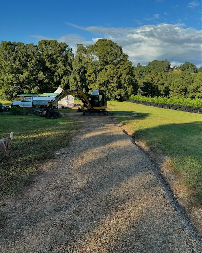 A Bulldozer is Driving Down a Dirt Road in a Field — Norcoast Diggers in Ballina, NSW