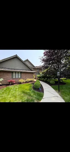 Brick building with green lawn and curved walkway lined with landscaping.