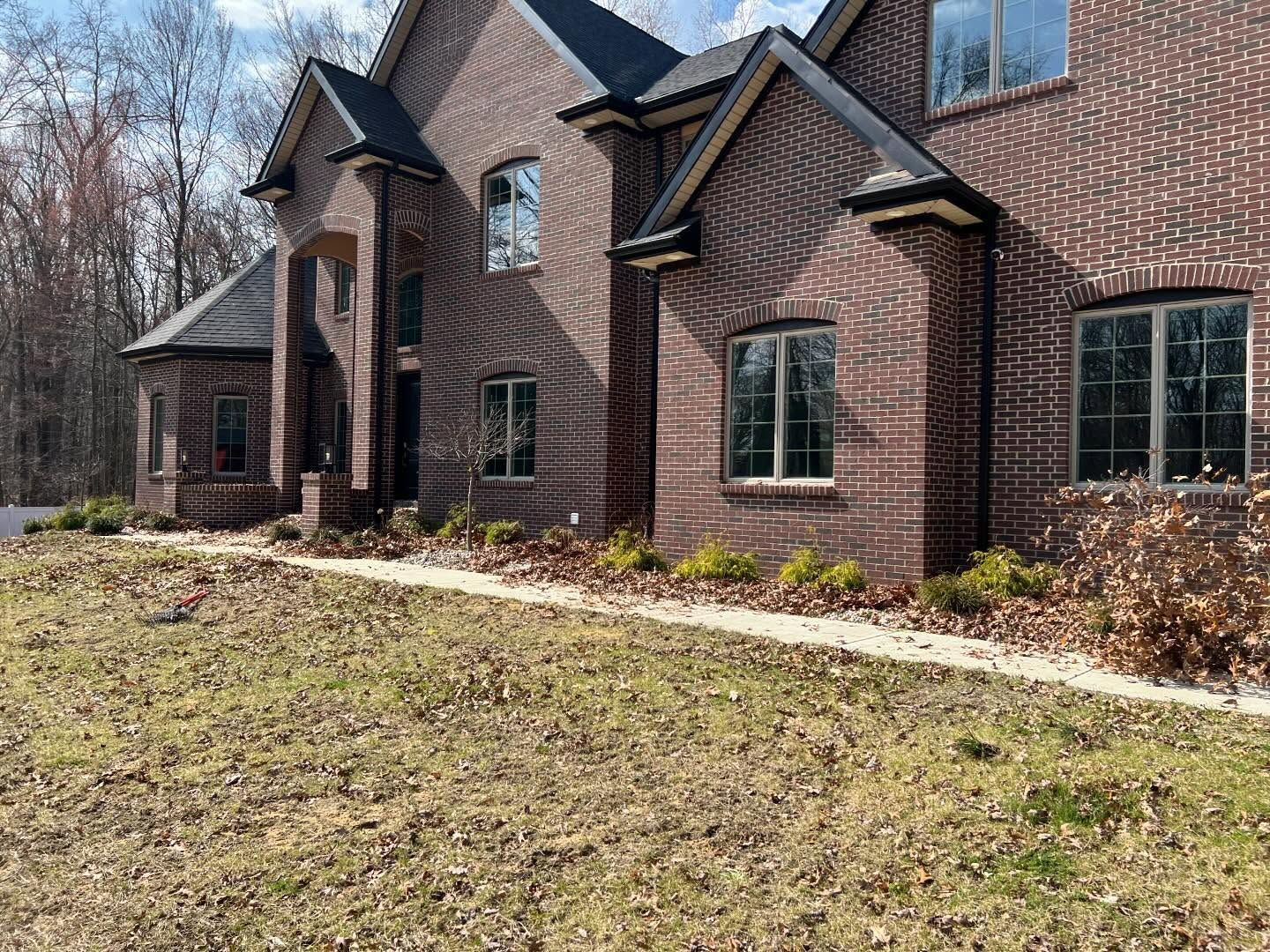 Brick home exterior with windows and landscaping; trees in background.