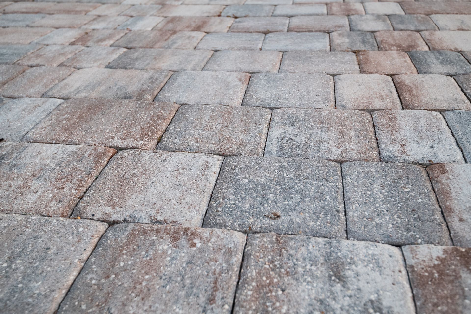 Close-up of a textured patio surface made of rectangular paving stones in blended shades of gray, brown, and tan.