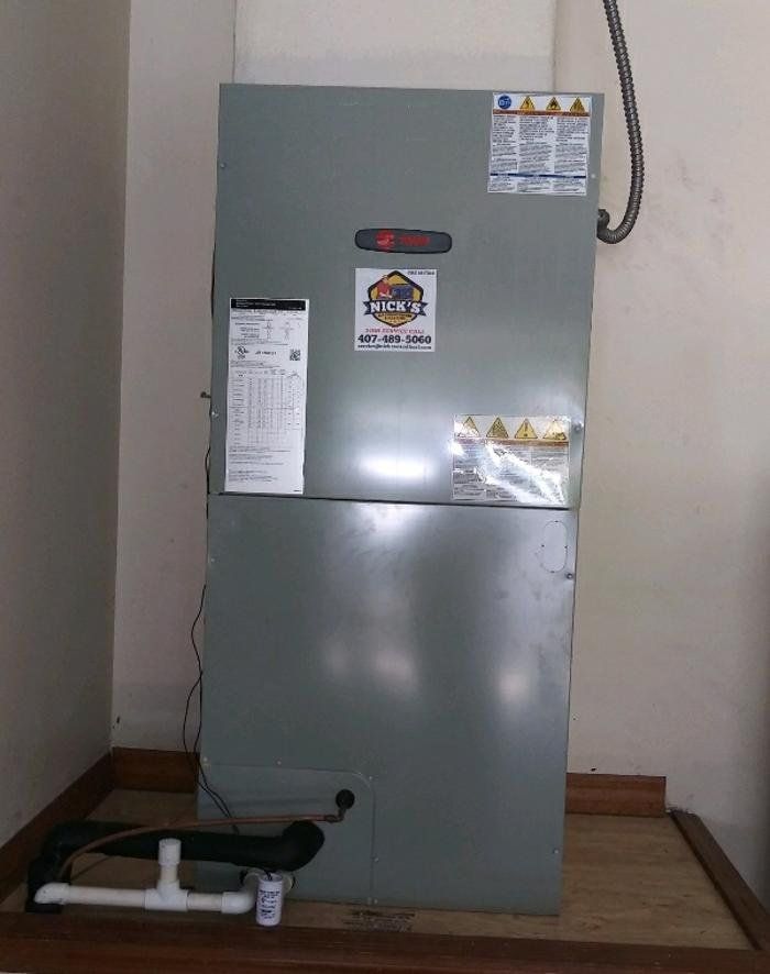HVAC unit in a room. Gray metal, stickers, and pipes.