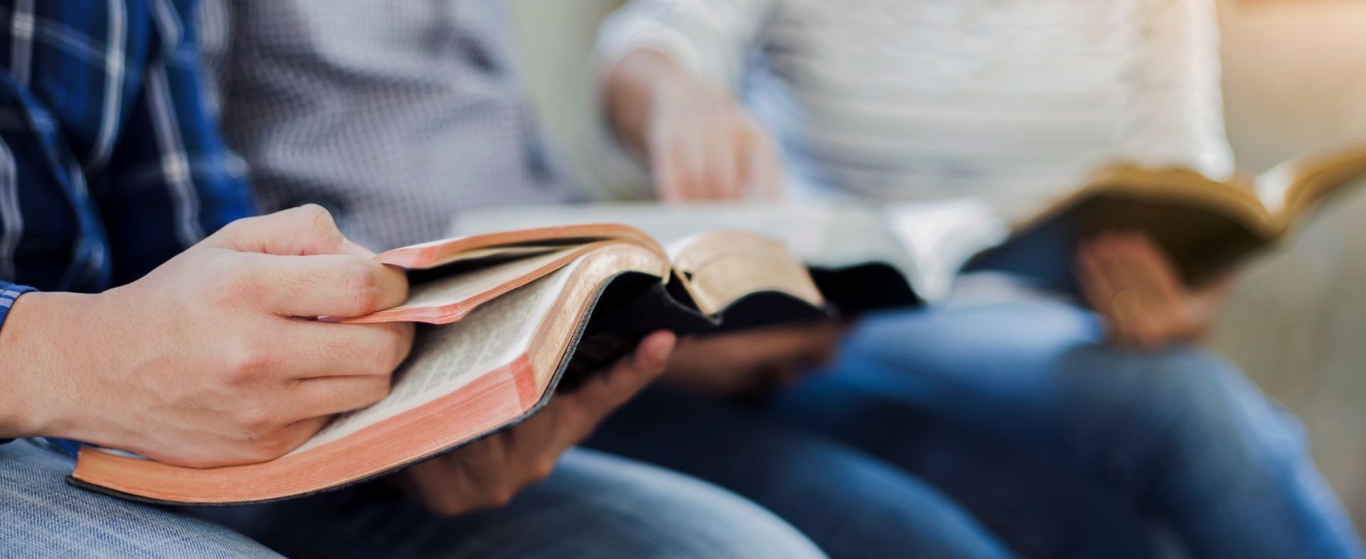 a person's hands holding a bible beside others