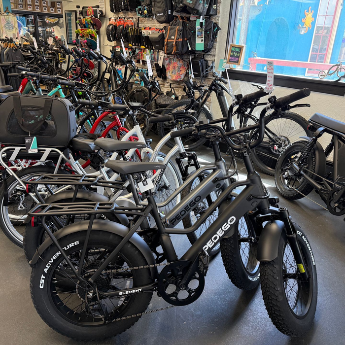 Bikes displayed in a shop, with several black fat-tire bicycles in the foreground.