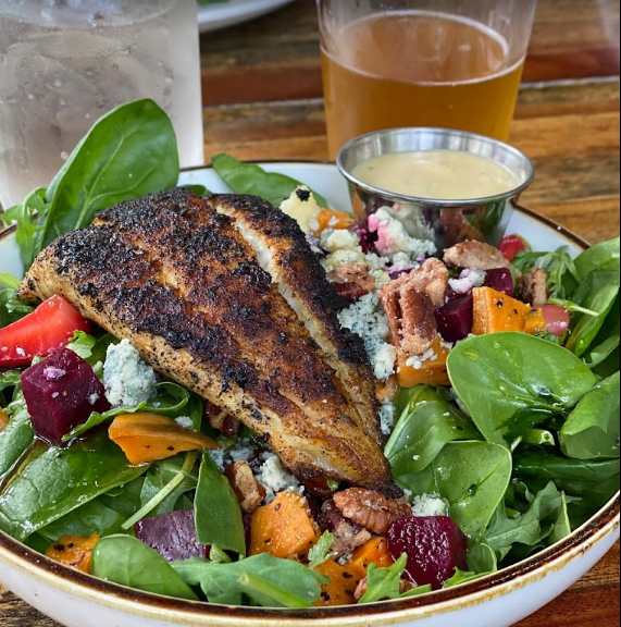 Grilled fish salad with roasted vegetables, blue cheese, pecans, and dressing.