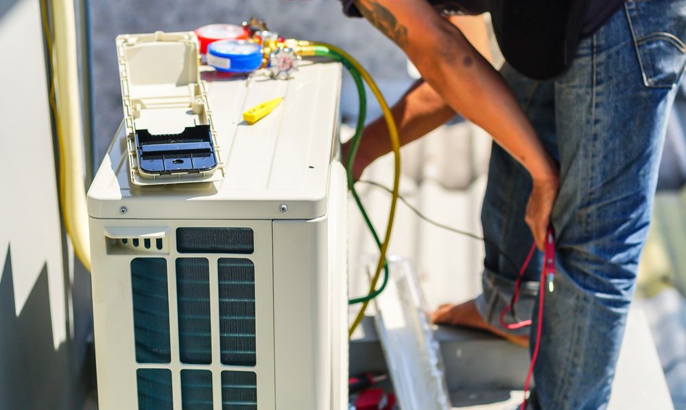 A Man Is Working On An Air Conditioner Outside Of A Building  — Law Air Conditioning In Magnetic Island, QLD