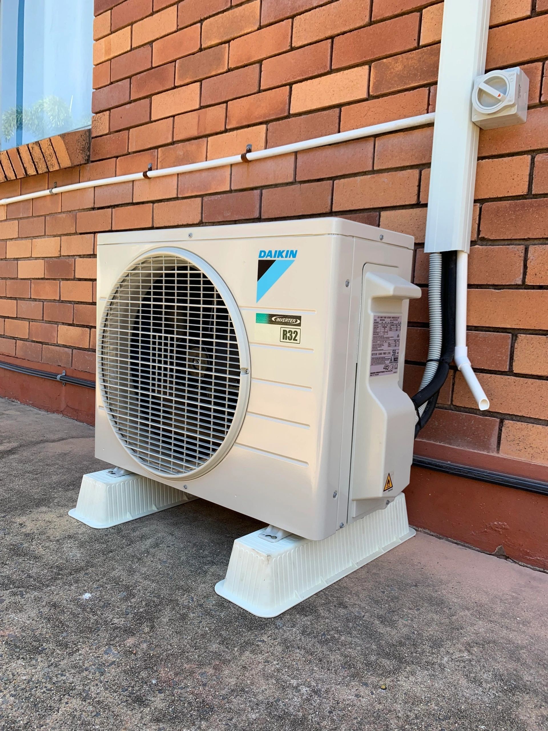 A Daikin Air Conditioner Is Sitting Outside Of A Brick Building — Law Air Conditioning In Annandale, QLD