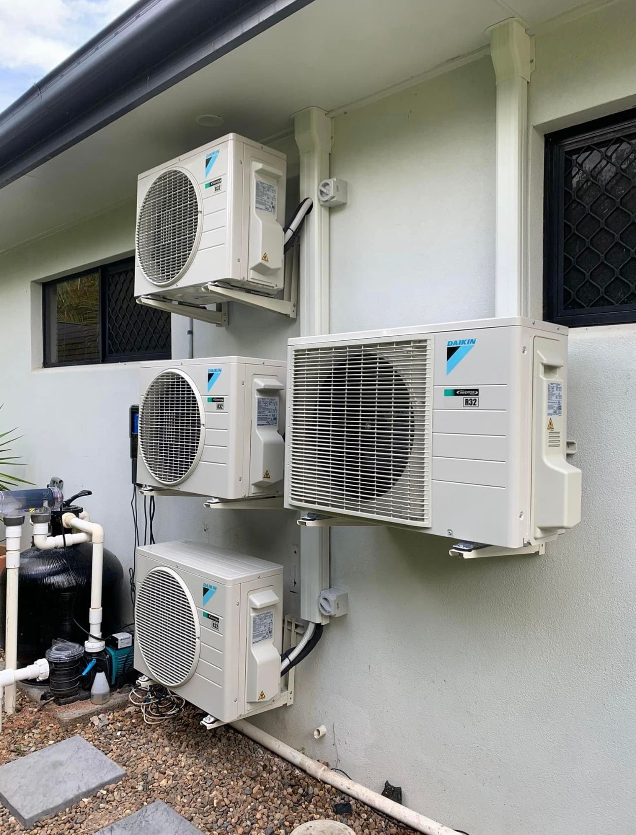Three Air Conditioners Are Mounted On The Side Of A House — Law Air Conditioning In Annandale, QLD