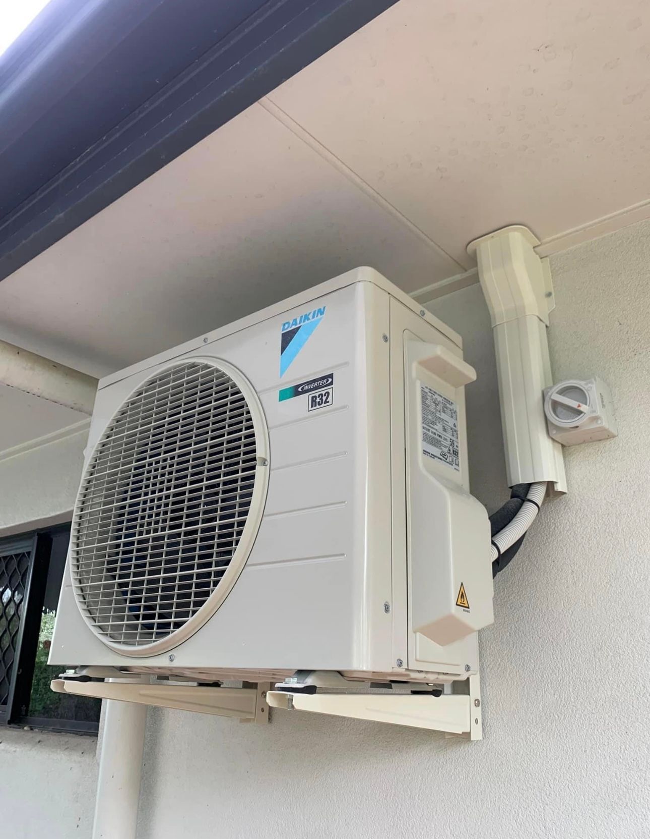 A White Air Conditioner Is Mounted On The Side Of A Building  — Law Air Conditioning In Annandale, QLD