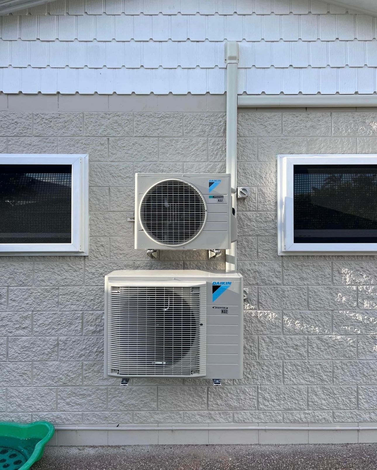 Two Air Conditioners Are Mounted On The Side Of A Brick Building — Law Air Conditioning In Annandale, QLD