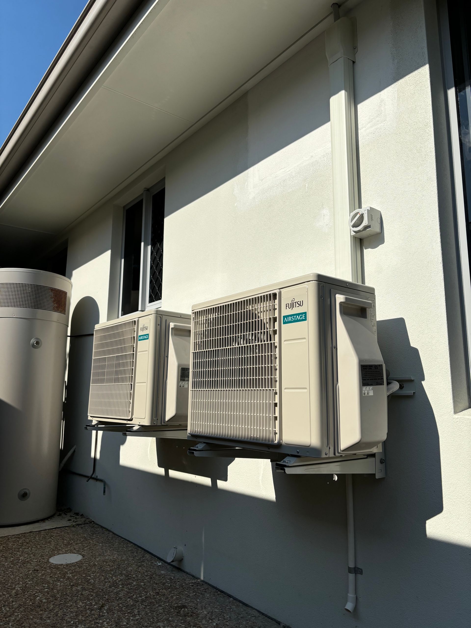 Two Air Conditioners Are Mounted On The Side Of A Building — Law Air Conditioning In Annandale, QLD
