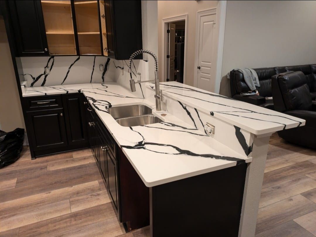 Modern kitchen with damaged or broken white marble countertop and black cabinets