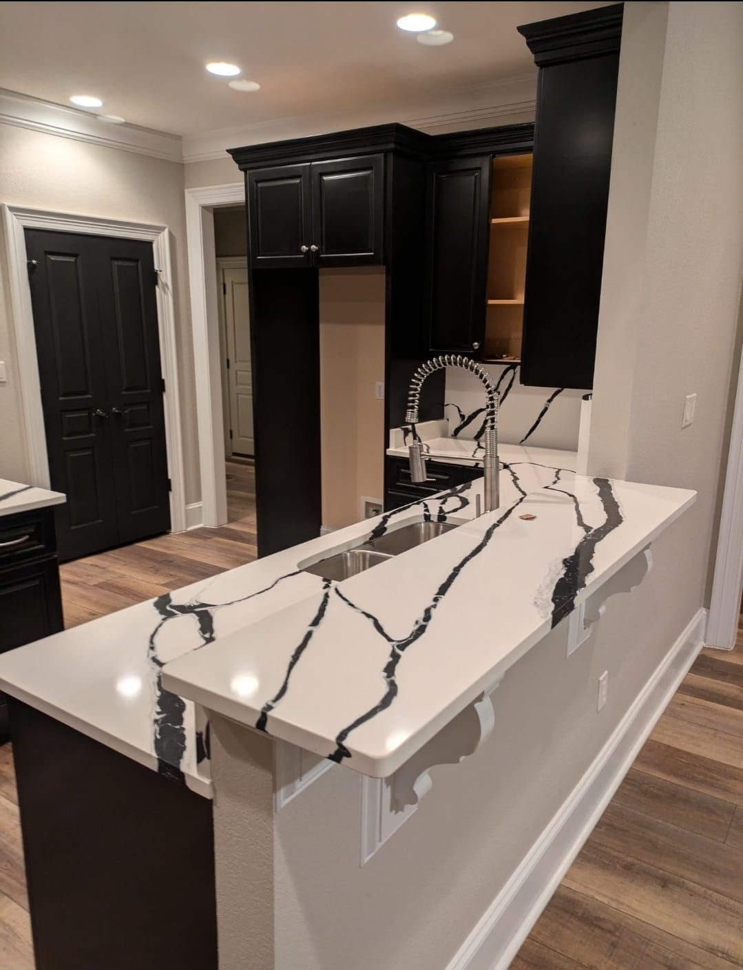 Modern kitchen with dark cabinets, white island, and marble-look countertop in a staged home interior