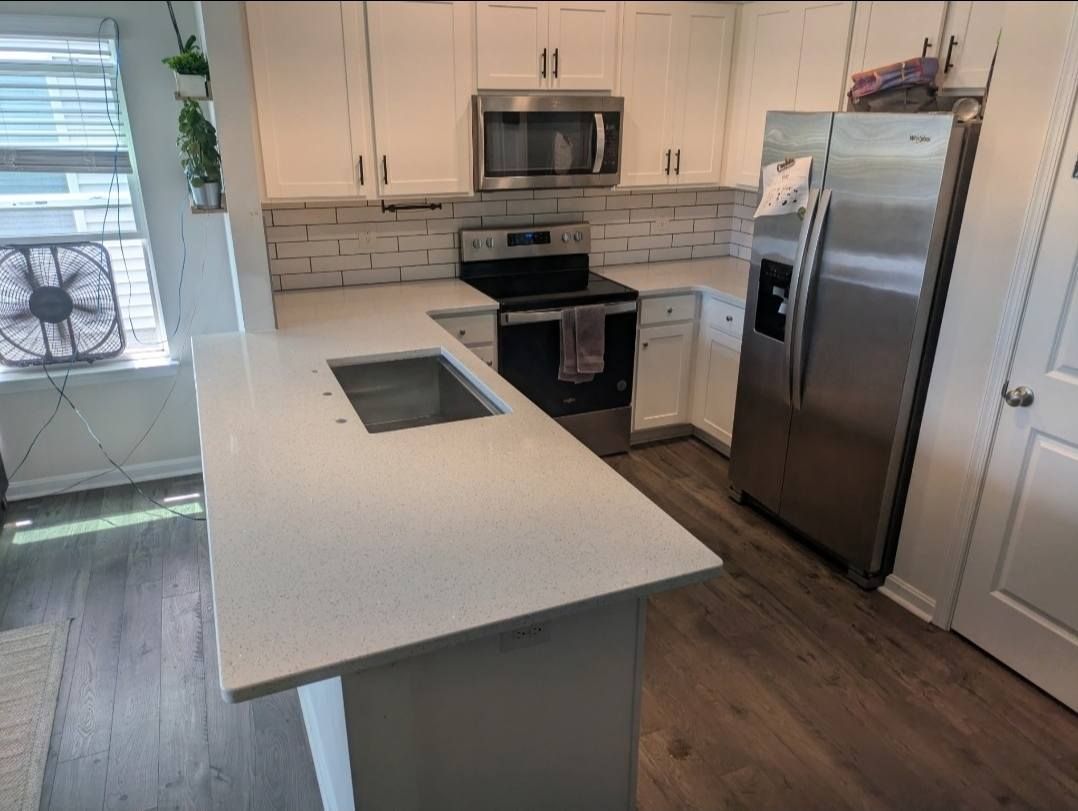Modern white kitchen with island, stainless steel appliances, and wood floor