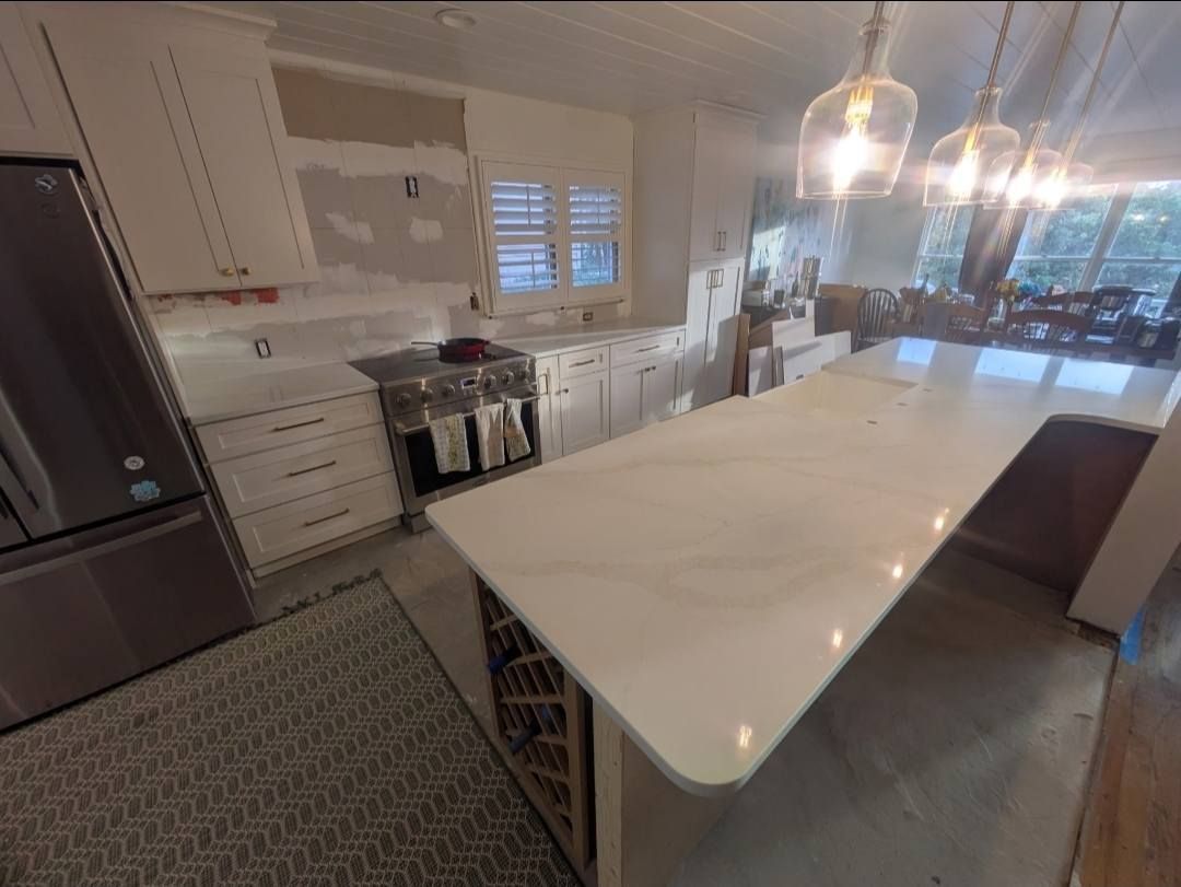 Modern white kitchen with a large island, stainless appliances, and pendant lights