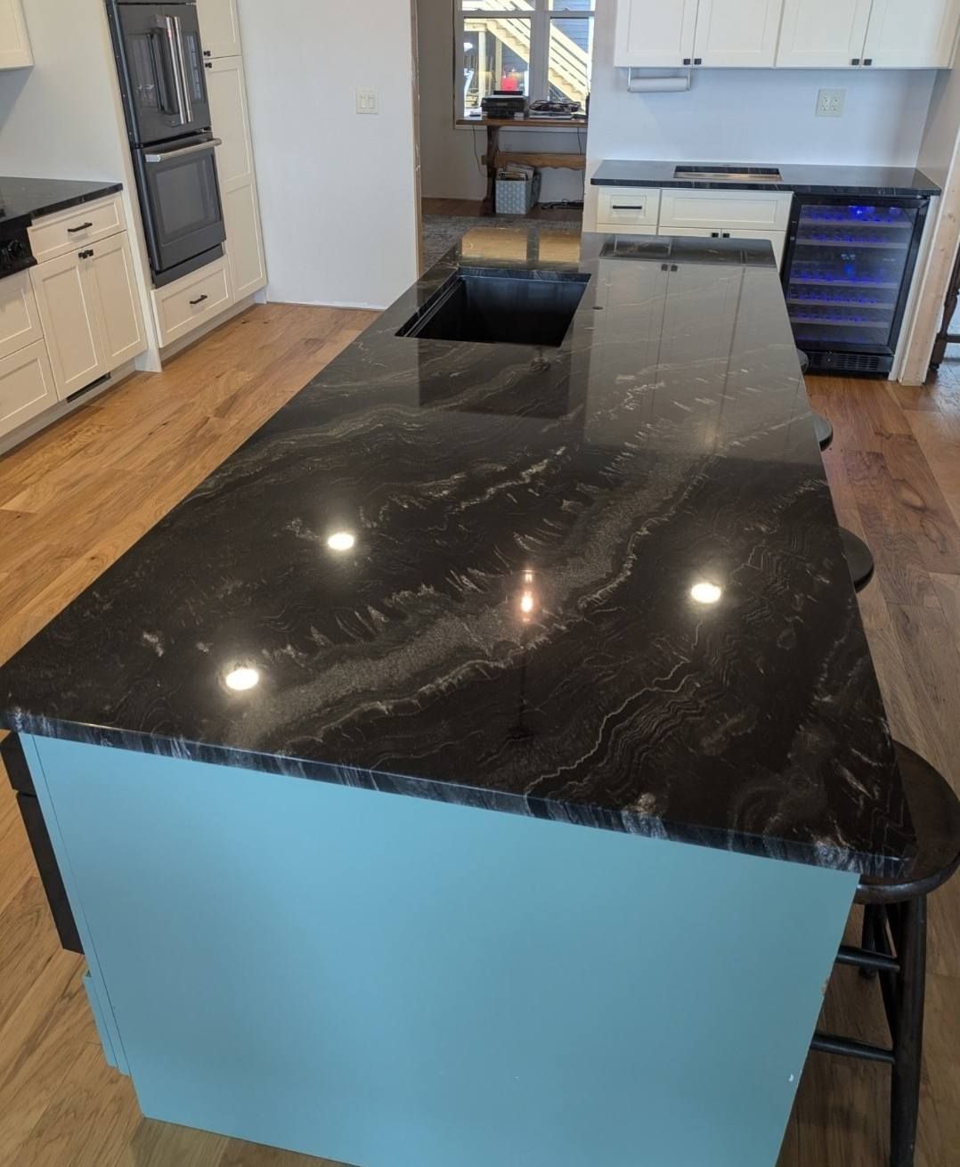 Modern kitchen with a glossy black island countertop and light blue island panels