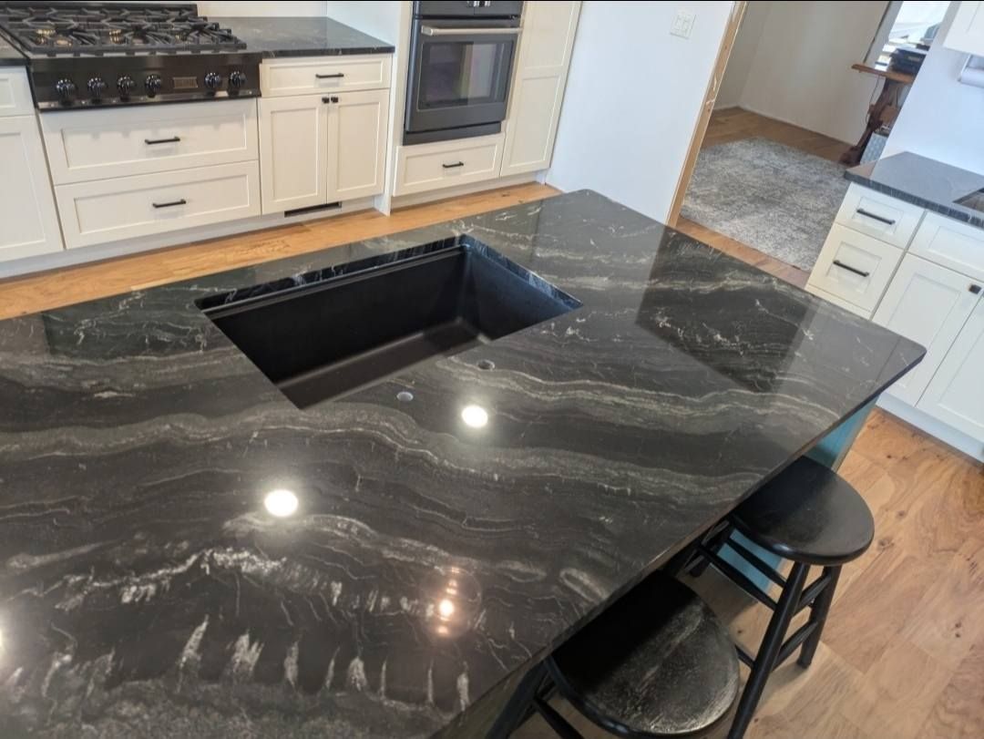 Black quartz kitchen island with built-in sink and two stools in a modern kitchen