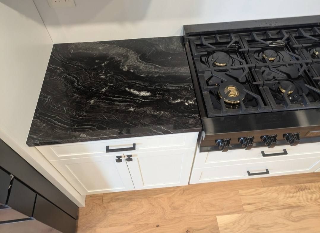 Damaged black cooktop with a scorched glass surface next to a gas stove in a kitchen