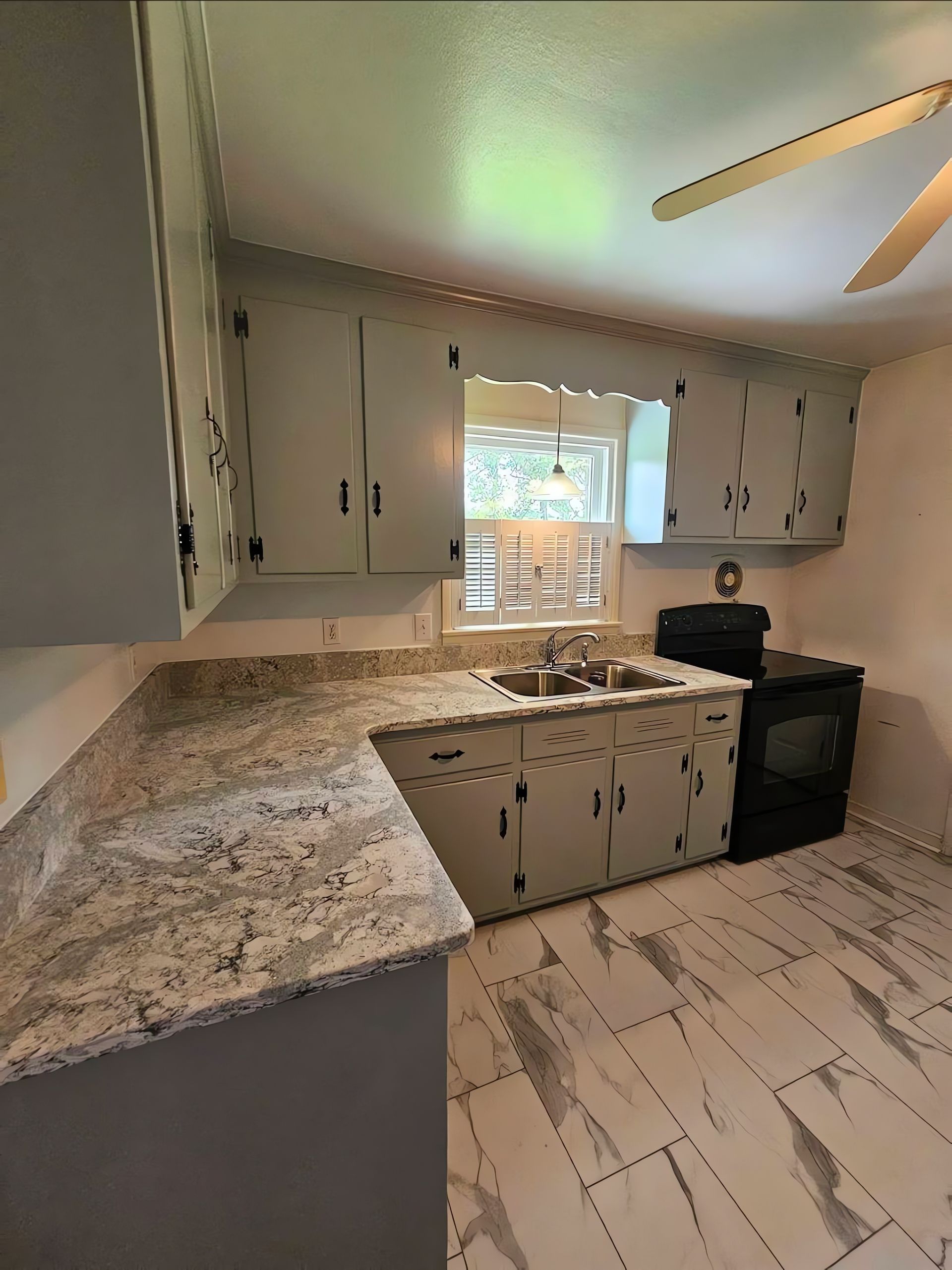Bright kitchen with marble island, wood cabinets, pendant lights, and a breakfast nook by large windows.