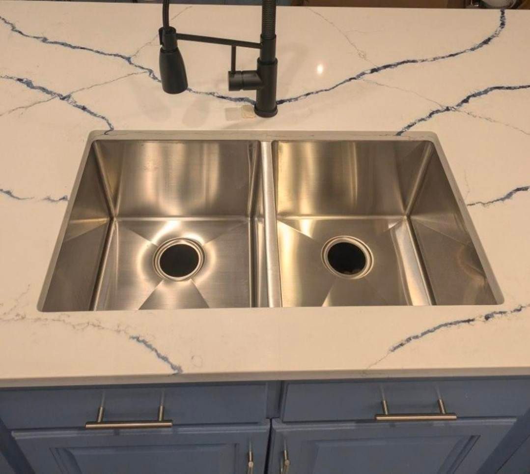 Double stainless-steel kitchen sink with black faucet and white marble countertop