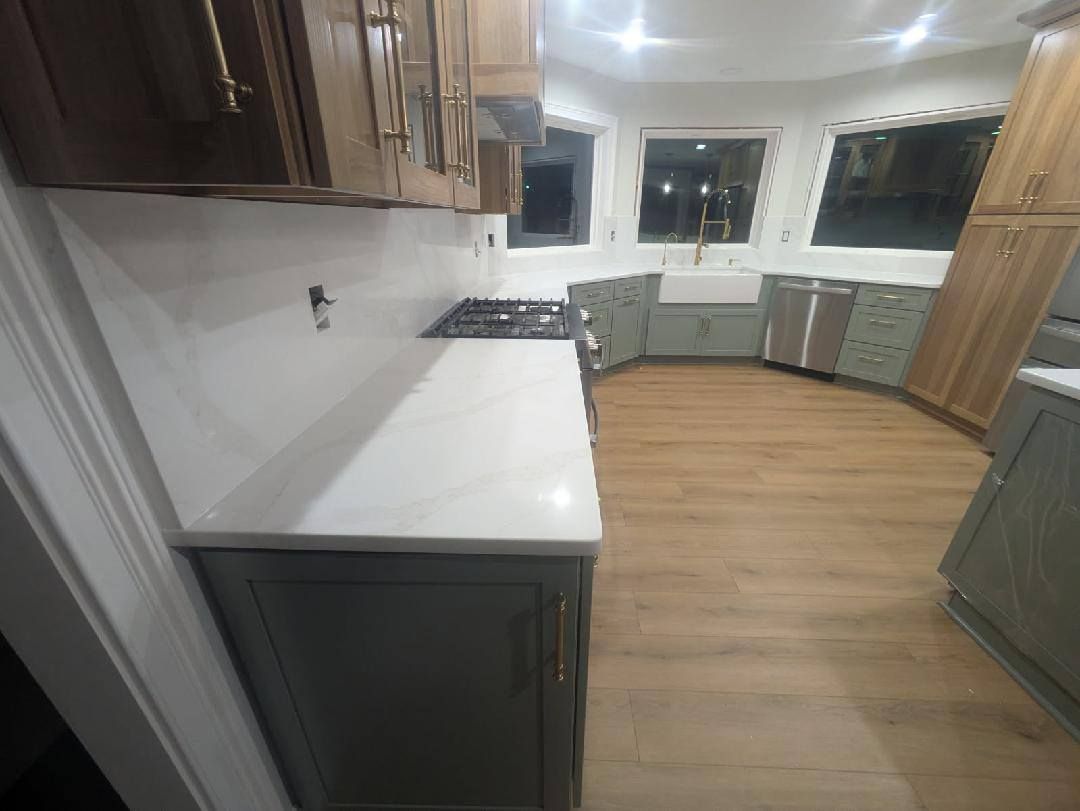 Modern kitchen with white countertops, dark cabinets, wood floor, and large windows.