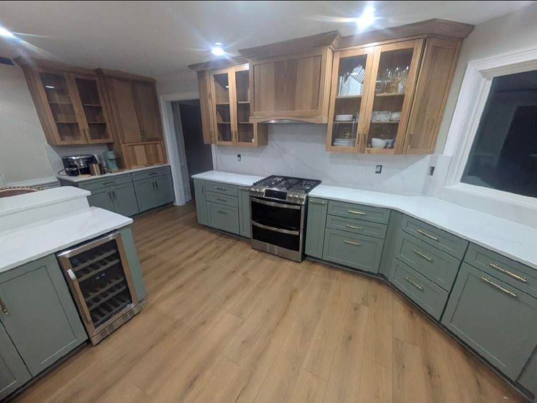 Modern kitchen with sage cabinets, wood accents, stainless stove, and light wood flooring
