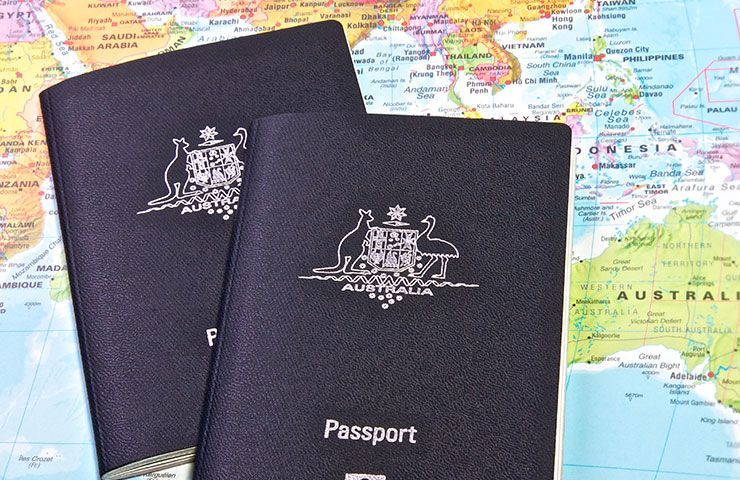 a person is holding a passport next to a brown duffel bag .