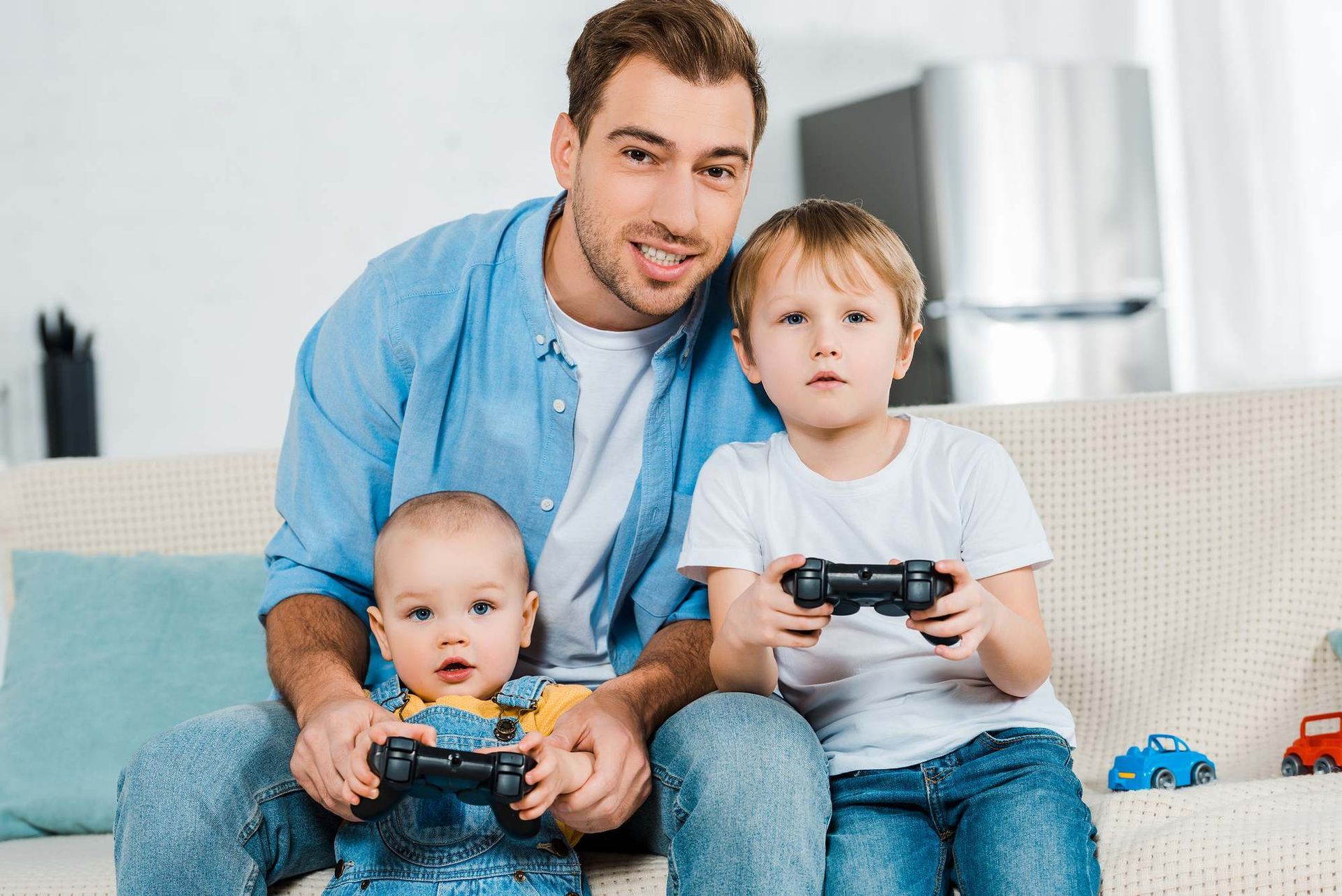 Father and two young children playing video games on a couch.