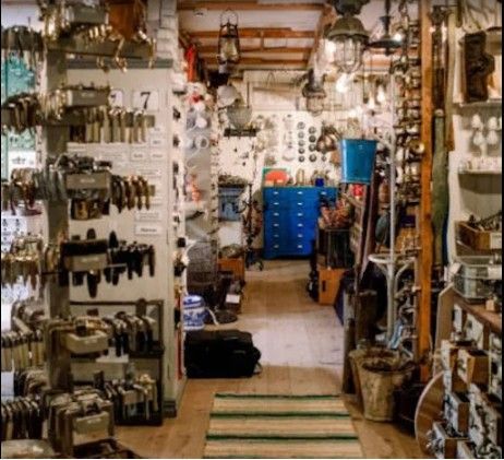 Interior de una tienda desordenada, llena de llaves, lámparas y herramientas viejas. 