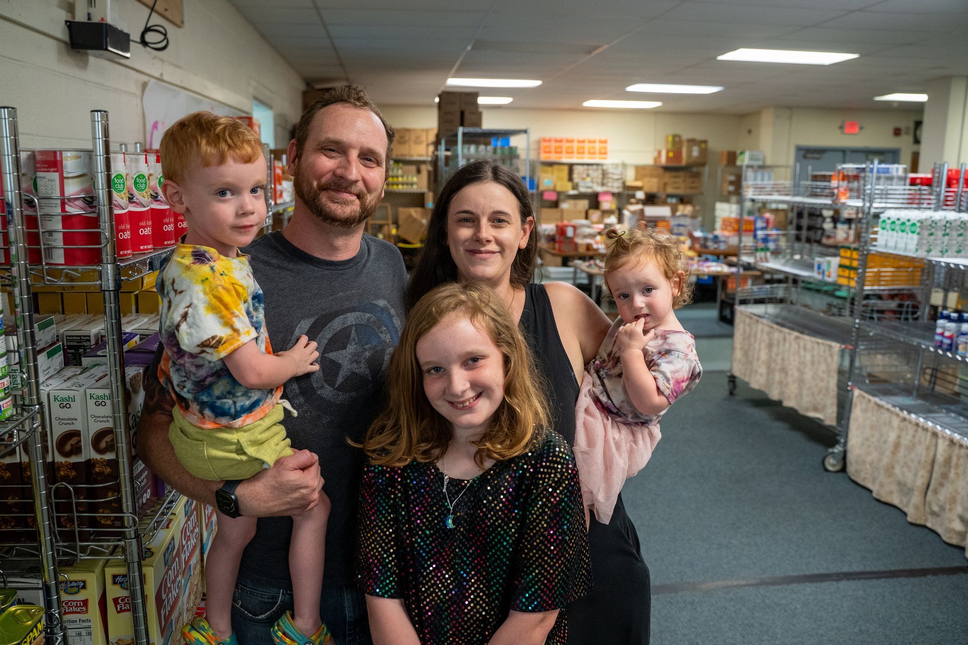 a family of five smiling for a photo taken in the food pantry they visit.