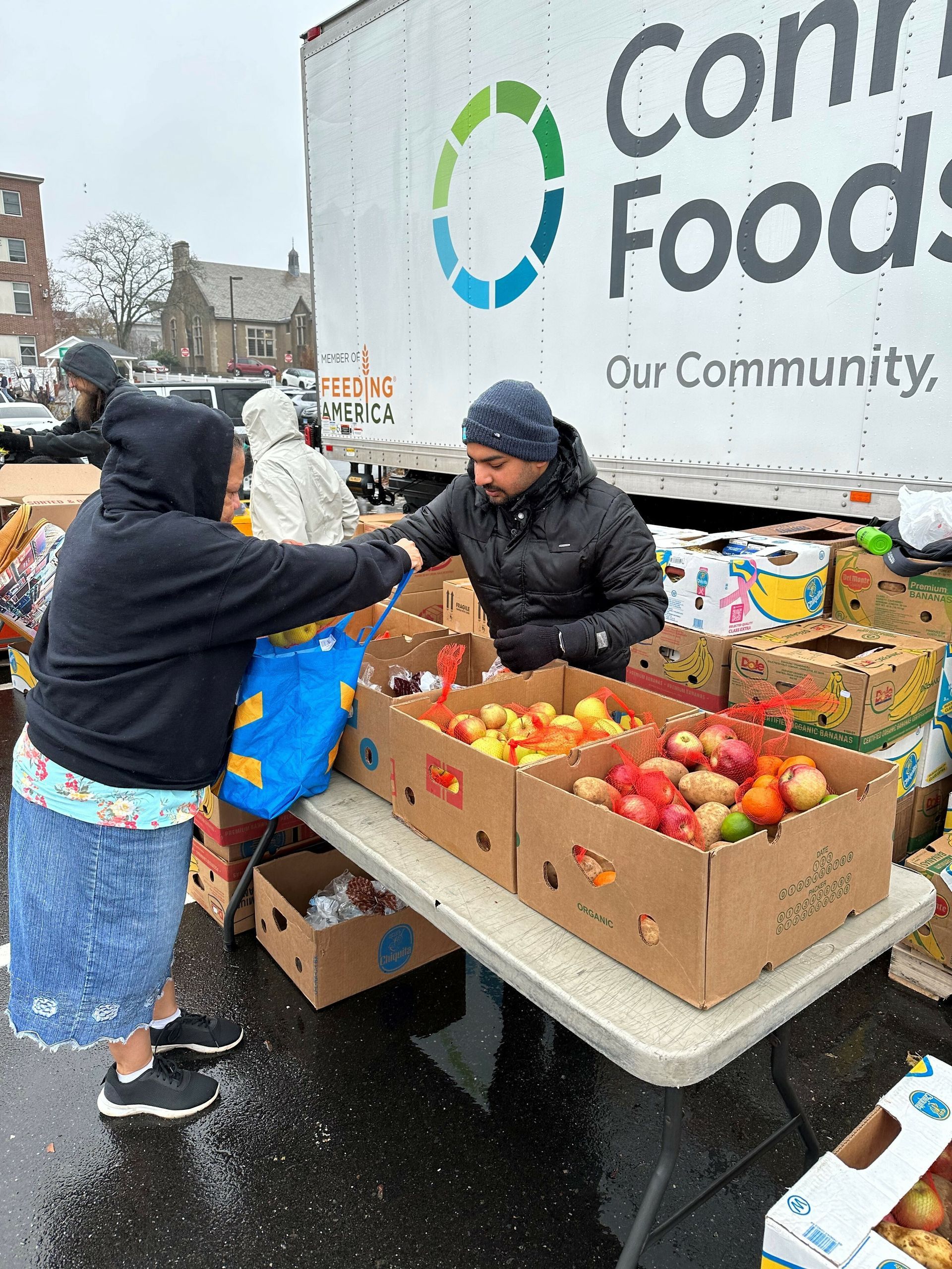 Volunteer assists a neighbor getting produce at a Connecticut Foodshare mobile food pantry.