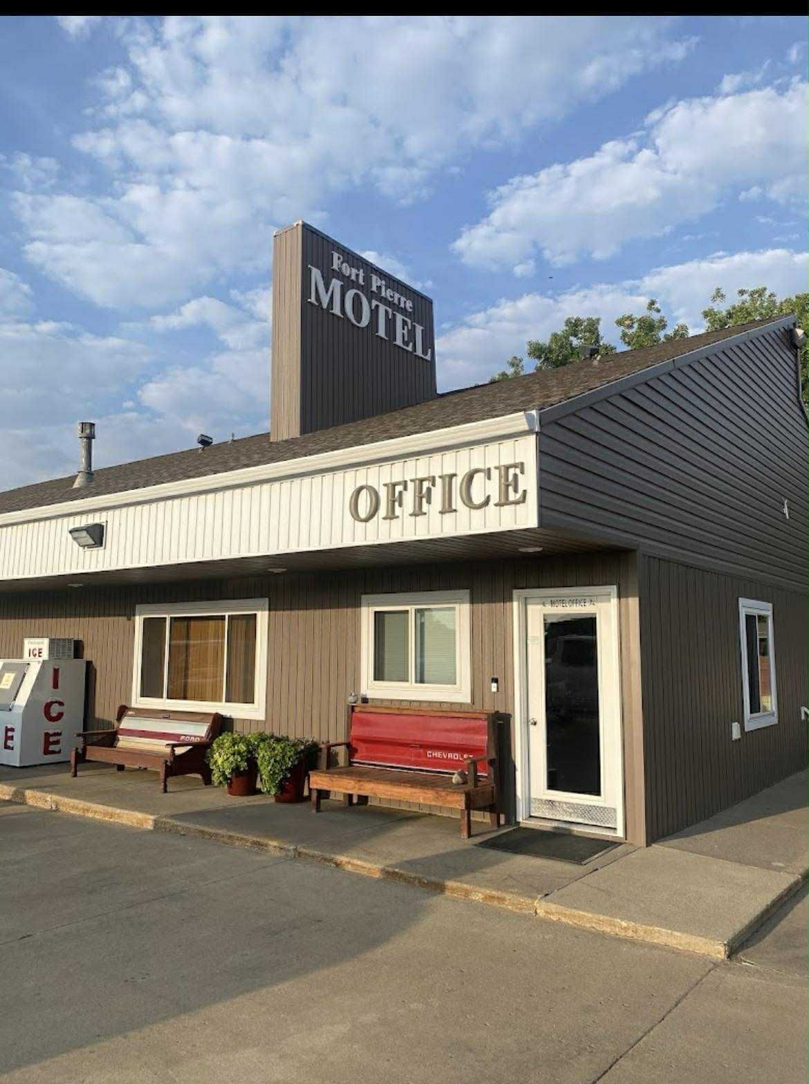A brown, one-story motel office building with a white sign reading 