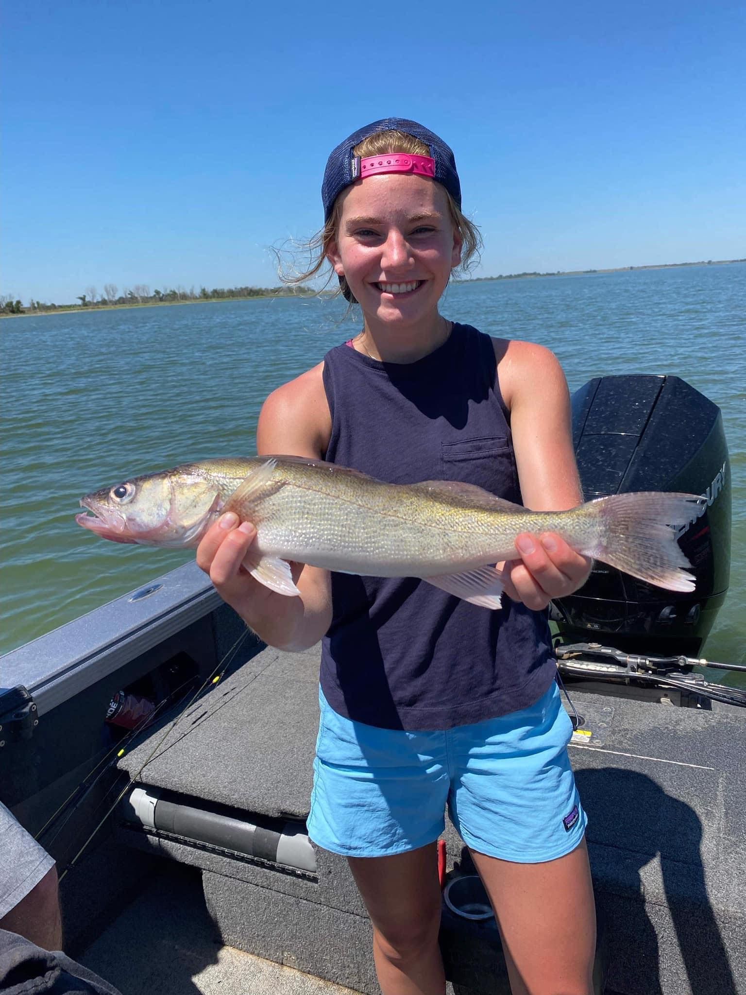Girl in blue shorts holding walleye on Lake Thompson, South Dakota