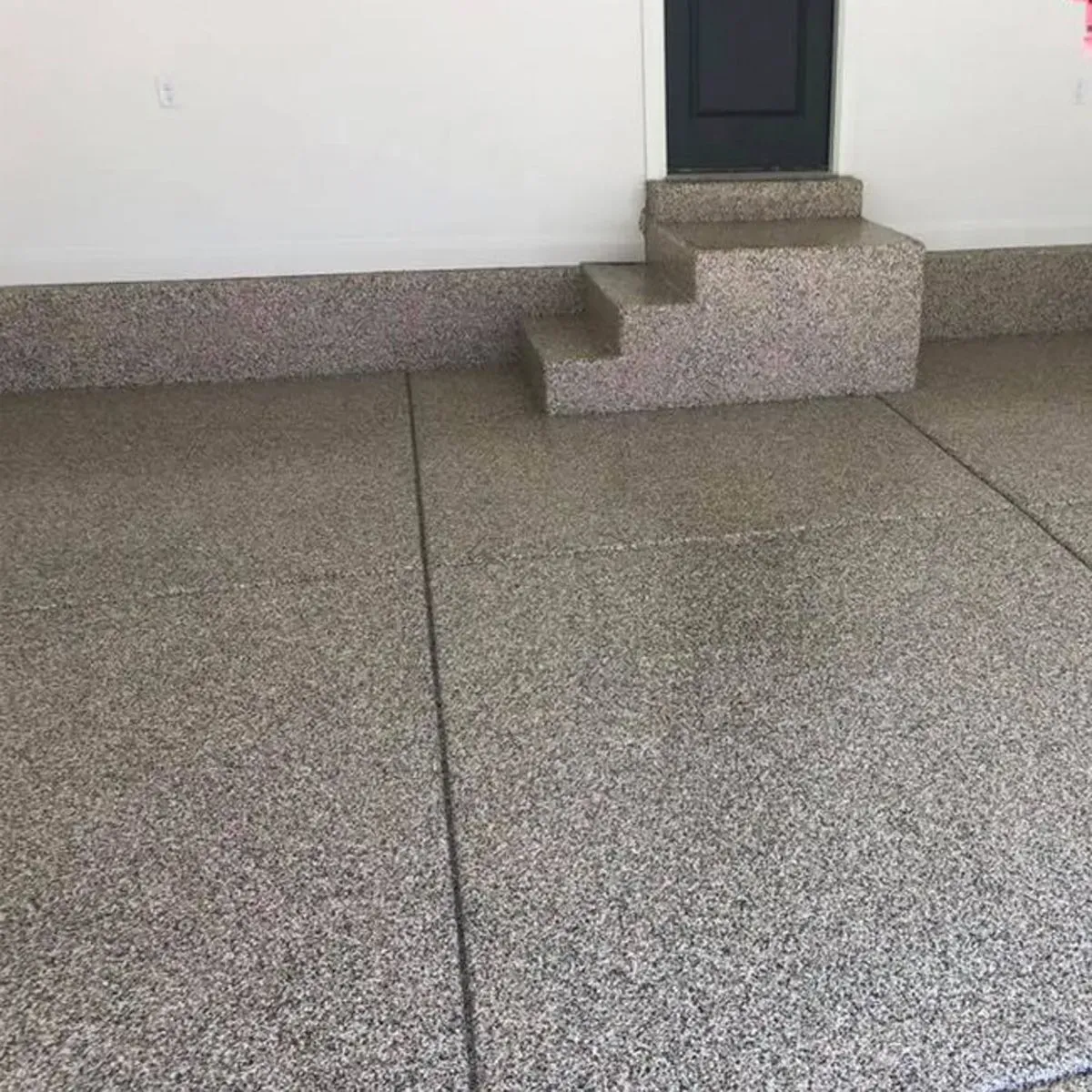 Garage with speckled epoxy floor and small steps leading to a doorway.