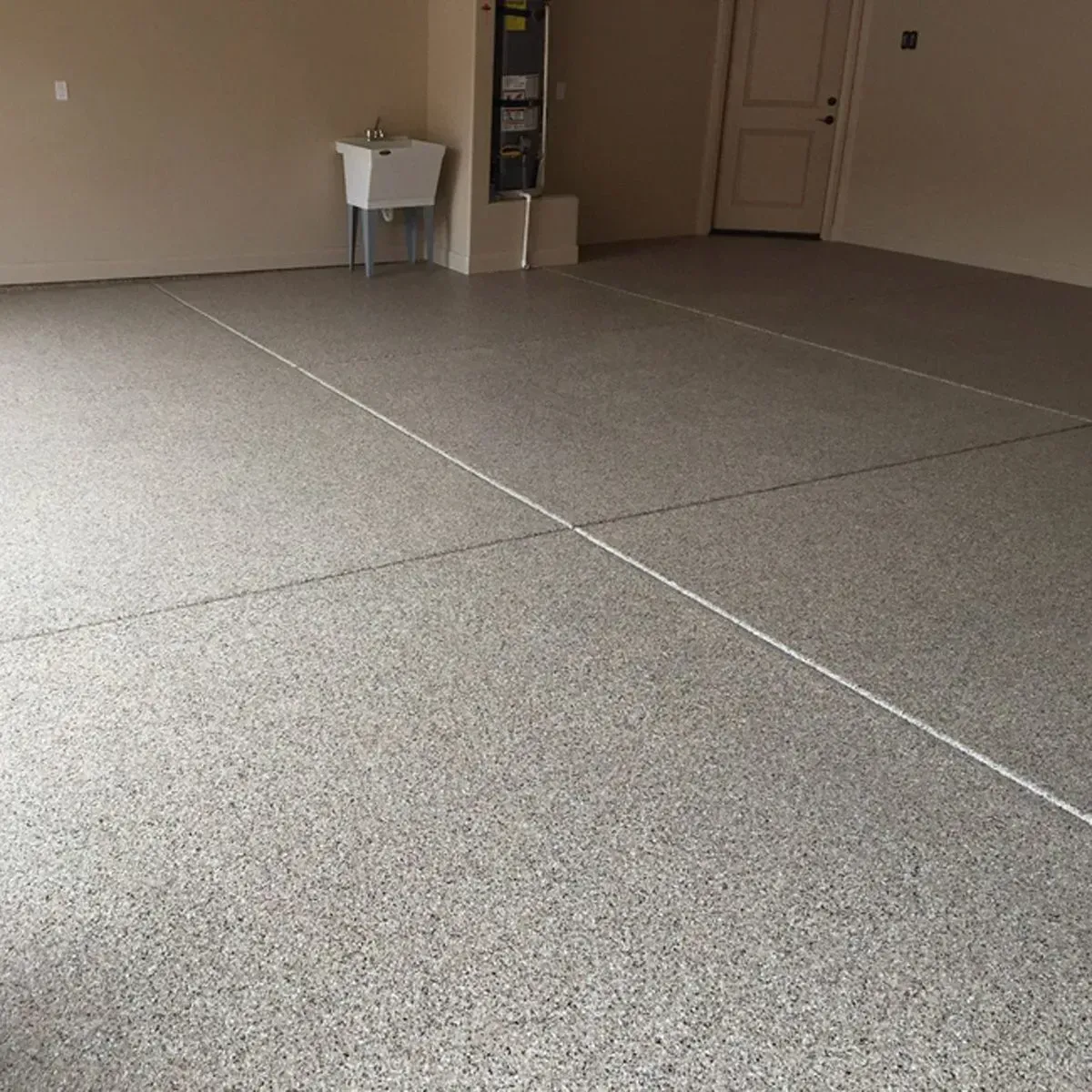 Garage with speckled, gray epoxy flooring, white lines, and a utility sink.