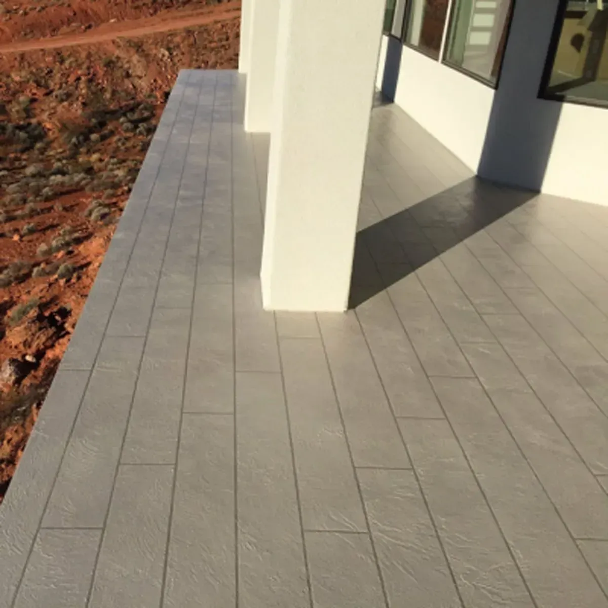 Gray tiled porch with white columns, red rocks in the background.