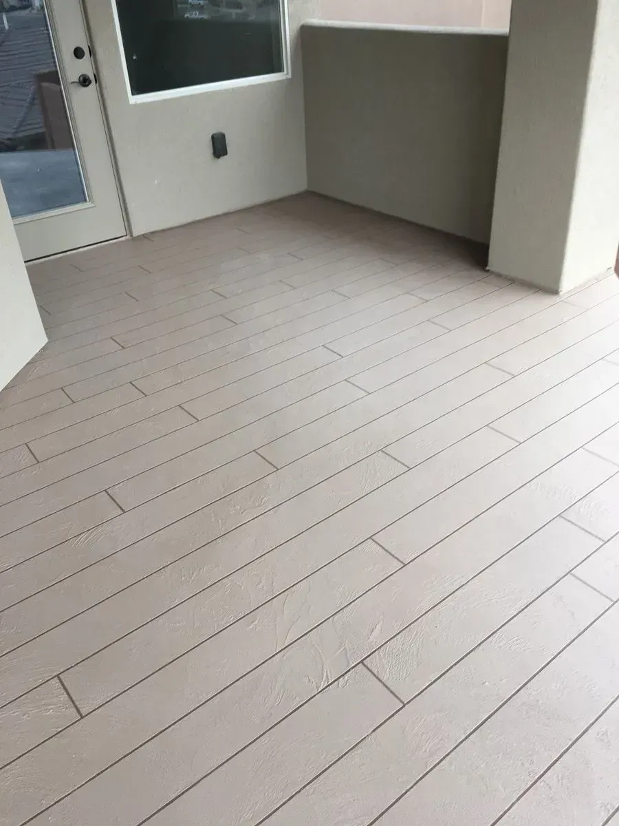 Beige wood-look tile flooring on a balcony, with a door and window visible.