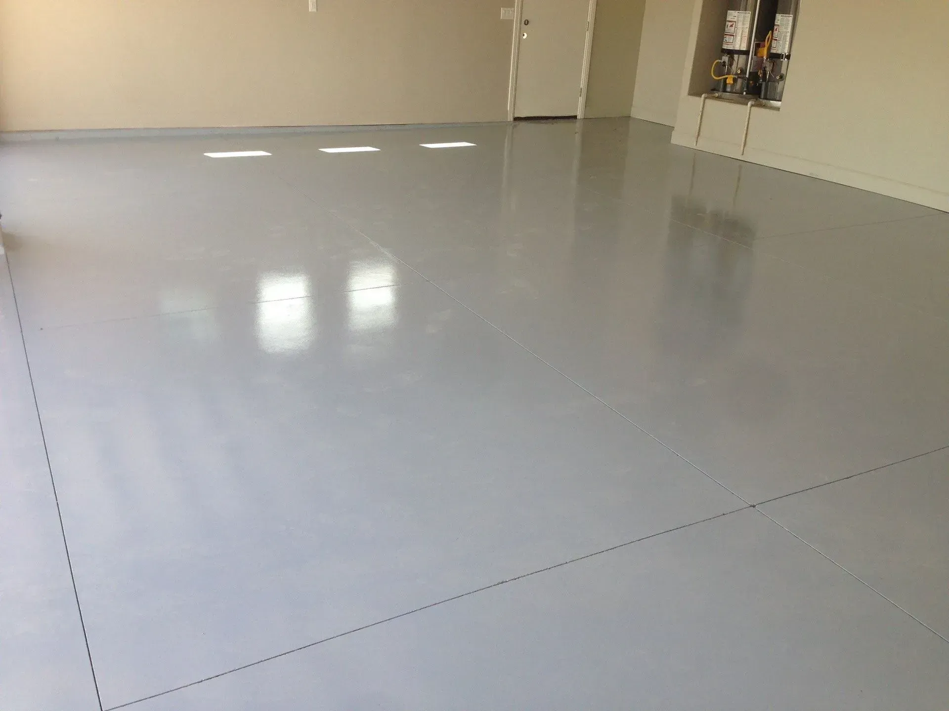 A light gray epoxy-coated garage floor reflecting overhead lights.