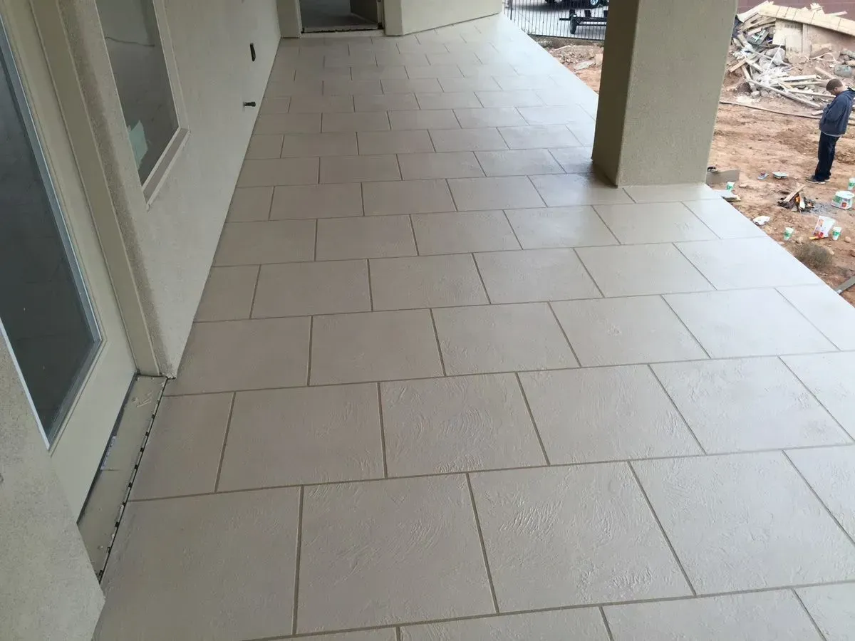 Covered patio with light beige tiled flooring, cream-colored walls, and a person in the background.